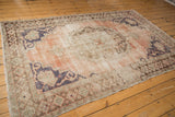 Corner of distressed vintage Oushak carpet, showing worn texture, foundation, dusty rose field.