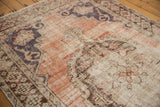 Worn dusty rose field with exposed knot heads and deep denim blue medallion edge.
