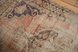 Distressed Oushak carpet: faded dusty rose and dark blue motifs with visible knot heads.
