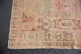 Close-up of distressed vintage Oushak rug, highlighting worn pile and blush, ivory Rococo contours.