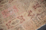 Distressed Oushak rug corner showing aged pile, antique ivory, blush, and wine red border.