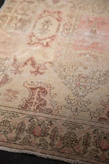 Distressed vintage Oushak rug showing worn pile and blush rose Rococo stylized border.