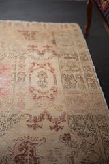 Distressed vintage Oushak rug, softly worn pile in ivory, blush, and faded rose patterns.