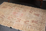 Distressed vintage Oushak rug detail: Rococo plant motifs in time-softened blush, rose, and ivory tones.