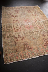 Worn pile and blush rose hues on the distressed Oushak rug's end with fringe.