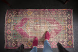 Vintage distressed Oushak rug corner with aubergine, mint, grey geometric motifs and wear.