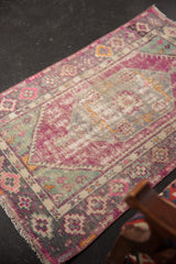 Decorative distressed vintage Oushak rug corner with vibrant pink, mint green, and grey floral motifs.