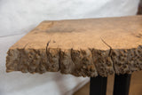 Live edge wooden table showing natural burl grain and surface cracks.