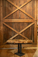 Textured reclaimed live edge wood tabletop with irregular edge and dark iron base.