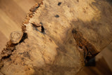 Natural live edge reclaimed wood tabletop featuring unique burl and dark grain patterns.