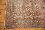Distressed vintage Sivas rug corner, showing faded brick red florals and slate blue border.