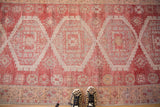 Distressed Oushak runner showing raspberry red and ivory serrated medallions with mostly even wear.