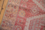 Textured pile of a distressed Oushak rug with muted raspberry, peach, and ivory hues and even wear.