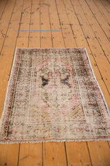 Distressed vintage Oushak rug corner; faded red, charcoal, ivory wear revealing foundation.