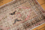 Distressed texture of a vintage Oushak rug, showing faded red, charcoal, and sand tones.
