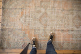 Distressed Oushak runner featuring geometric medallions in faded tangerine, ivory, and silver.
