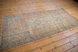 Distressed vintage Oushak rug corner, featuring geometric border and visible wear to knot heads.