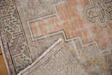Folded corner reveals hand-knotted Oushak foundation, distressed tangerine and silver geometric pile.