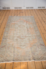 Distressed Oushak runner with faded tangerine, silver, and ivory geometric double medallion design.