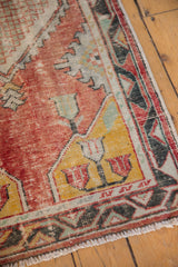 Distressed vintage Oushak runner corner, faded red field, saffron yellow patterns, geometric border.