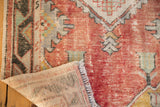 Distressed Oushak runner with hand-knotted back and fringe, showing faded red pile texture.