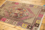 Vintage distressed Oushak rug's decorative pile, featuring faded mauve, pink, and blue motifs.