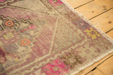 Fringe and textured pile of a distressed Oushak rug, with faded mauve, beige, and yellow hues.