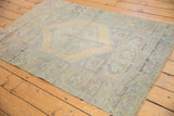 Distressed vintage Oushak rug corner showing worn knot heads and soft mint green.