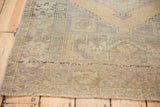 Distressed vintage Oushak rug corner showing stepped spandrel and low pile in soft greens.