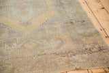 Distressed Oushak rug edge with worn low pile and frayed fringe in pale mint green.