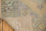 Vintage Oushak rug's folded corner: distressed low pile, lemon sand, mint green, and woven foundation.