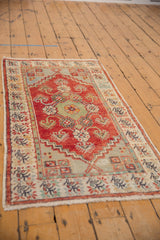 Distressed Oushak runner showing low pile, cherry red field, and colorful floral motifs.