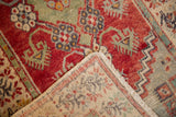 Vintage Oushak runner folded, revealing hand-knotted foundation, fringe, and distressed red pattern.
