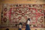 Distressed Oushak rug's large floral cross sections in cherry red and beige.