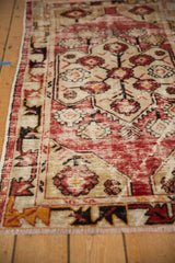 Distressed vintage Oushak rug detail: cherry red field, floral cross sections, vine border.