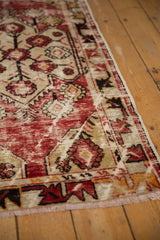 Distressed cherry red and beige main field texture with meandering vine border of vintage Oushak rug.