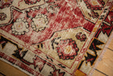 Distressed Oushak rug runner corner, with cherry red, beige, and tangerine vine border.