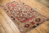 Distressed Oushak runner corner, showing worn cherry red and beige field, patterned border, and fringe.