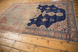 Corner of distressed Sivas rug, showing navy field, blush scalloped motifs, and patterned border.