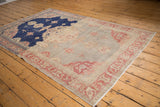 Distressed Sivas rug corner with abrashed silver field, pale raspberry motifs, and visible wear.