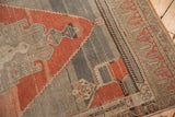 Distressed Oushak runner's textured abrash field with blush rust geometric detail.