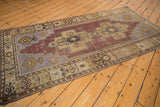 Distressed vintage Oushak runner with double medallion, floral border, aubergine and sand tones.