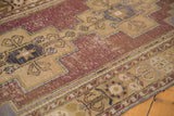 Distressed aubergine field and geometric sand border with visible wear on Oushak runner.