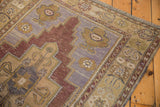 Distressed aubergine and sand tones on the Oushak rug's germinating flower border.