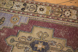 Worn pile and exposed foundation detail on a distressed Oushak rug in aubergine, sand, and pale blue.
