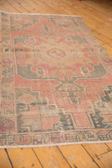Distressed Oushak pile texture highlighting the simplistic flower and vine border in dusty rose and charcoal.