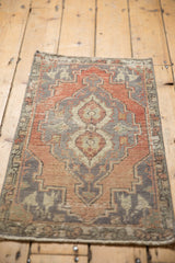 Distressed Oushak rug mat corner showing blush rose, silver, and ivory geometric medallion wear.