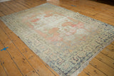 Distressed corner of a vintage Oushak rug with blush, silver, and charcoal patterns.