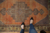 Distressed Oushak rug runner with geometric stepped medallion and finials in pale rust, blue, and green.