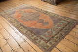 Corner of vintage distressed Oushak rug, with stepped medallion and pale green border.